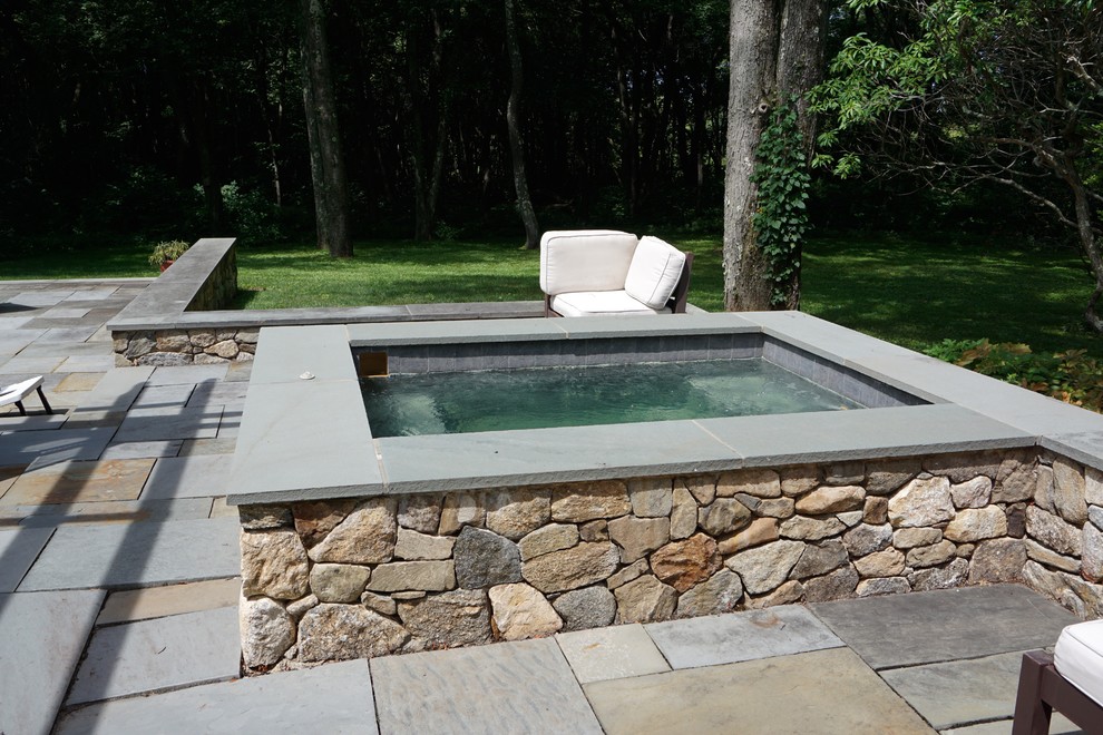 Ejemplo de piscinas y jacuzzis elevados minimalistas pequeños rectangulares en patio trasero con adoquines de piedra natural