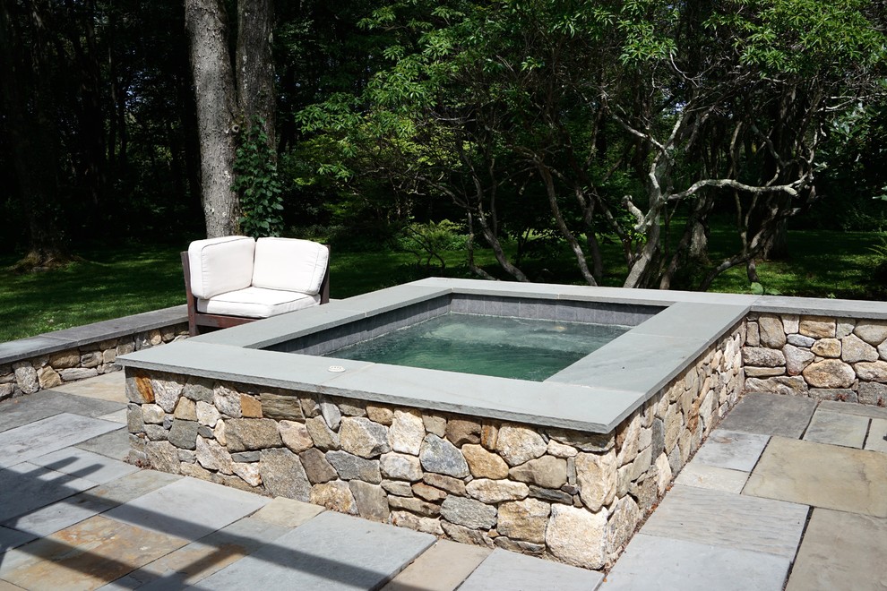 Ejemplo de piscinas y jacuzzis elevados minimalistas pequeños rectangulares en patio trasero con adoquines de piedra natural