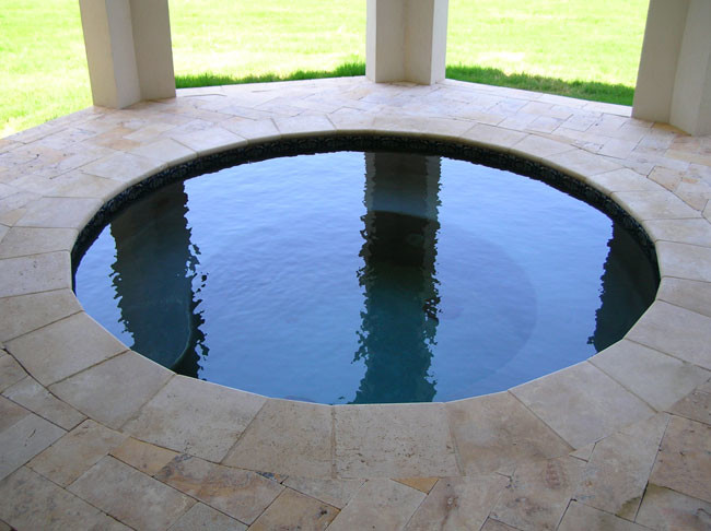 Exemple d'une piscine arrière montagne de taille moyenne et ronde avec un bain bouillonnant et des pavés en pierre naturelle.