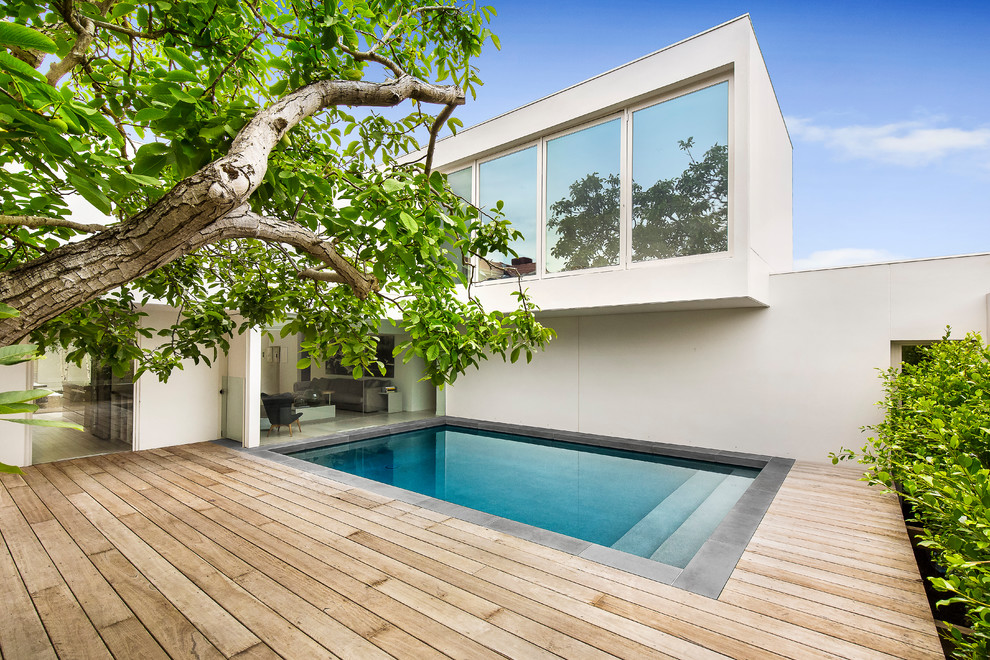 Cette image montre une petite piscine minimaliste rectangle avec une terrasse en bois.