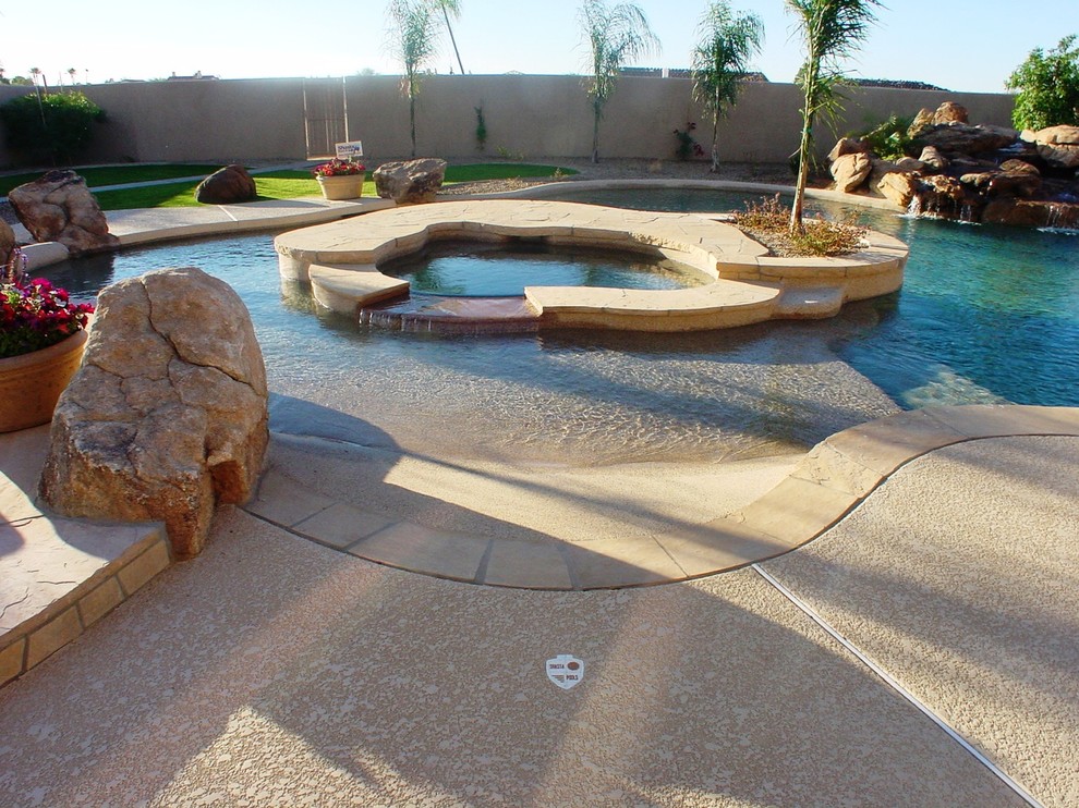 Photo of a world-inspired back custom shaped swimming pool in Phoenix with concrete slabs.