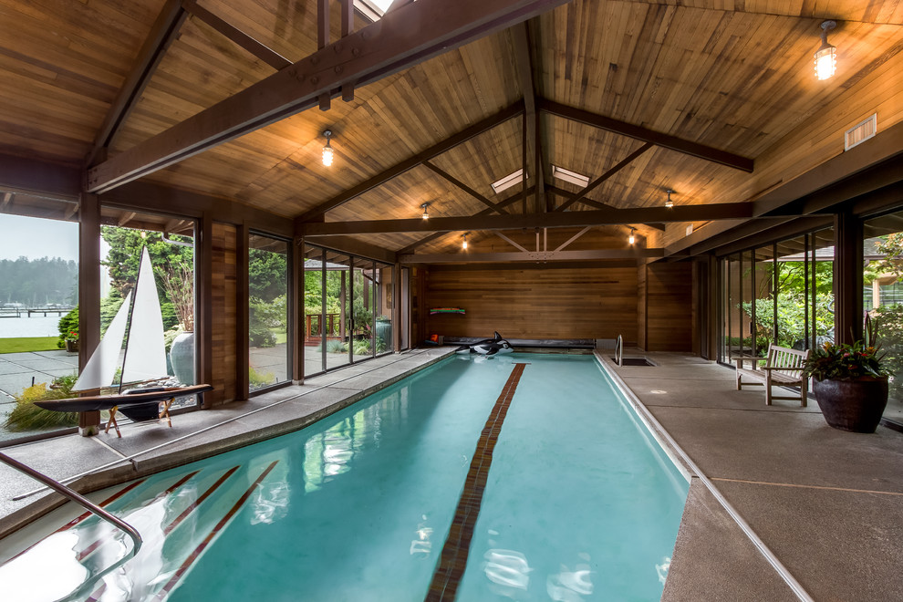 На фото: большой спортивный, прямоугольный бассейн в доме в стиле рустика с домиком у бассейна и покрытием из декоративного бетона