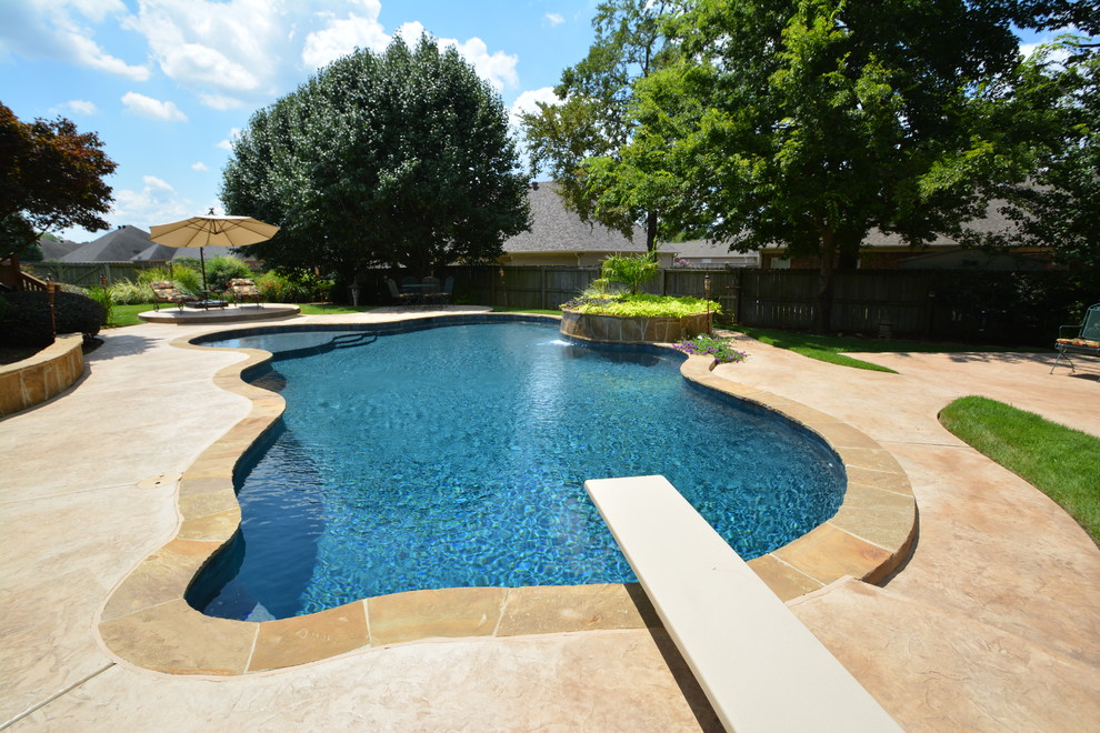 Inspiration for a large traditional back custom shaped lengths swimming pool in Little Rock with a water feature and stamped concrete.