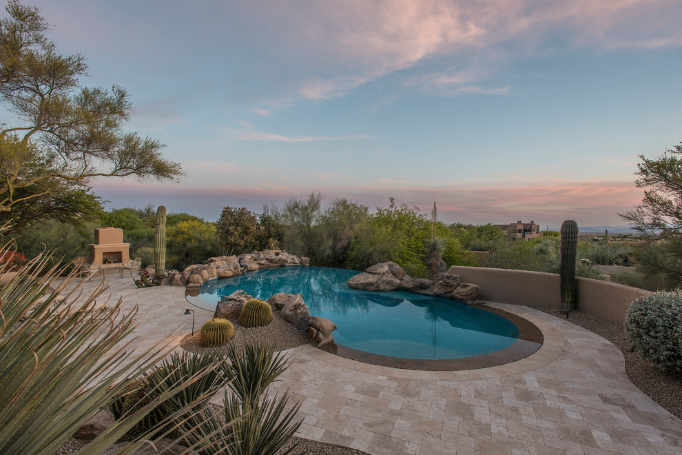 Ispirazione per una grande piscina a sfioro infinito stile americano personalizzata dietro casa con pavimentazioni in pietra naturale