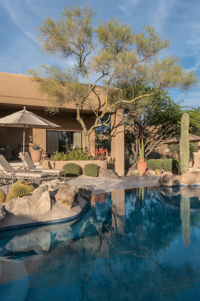Foto de piscina infinita de estilo americano grande a medida en patio trasero con adoquines de piedra natural