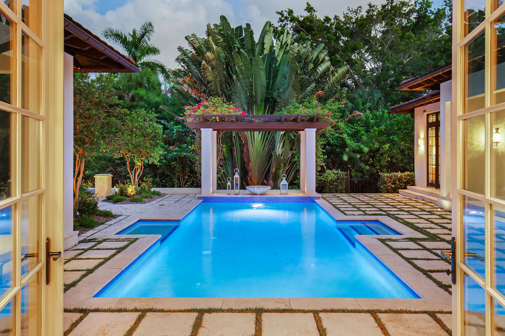 Diseño de piscina alargada exótica de tamaño medio rectangular en patio trasero con adoquines de hormigón