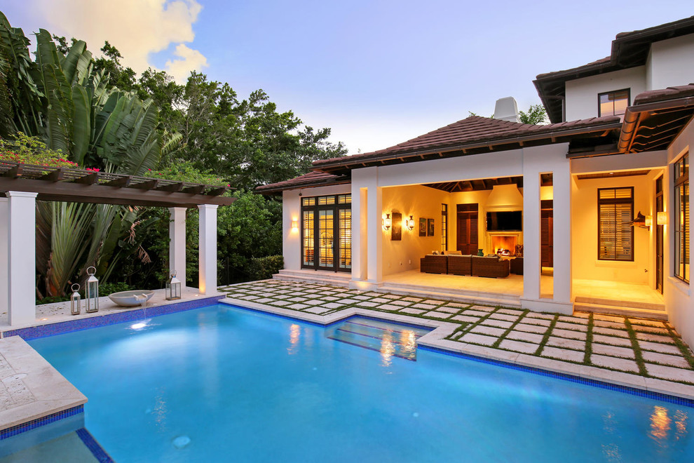Modelo de piscina alargada exótica de tamaño medio rectangular en patio trasero con adoquines de hormigón
