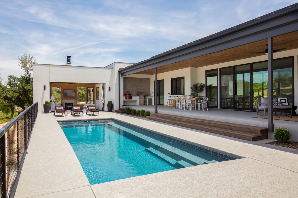 На фото: спортивный, прямоугольный бассейн среднего размера на заднем дворе в современном стиле с домиком у бассейна и покрытием из декоративного бетона