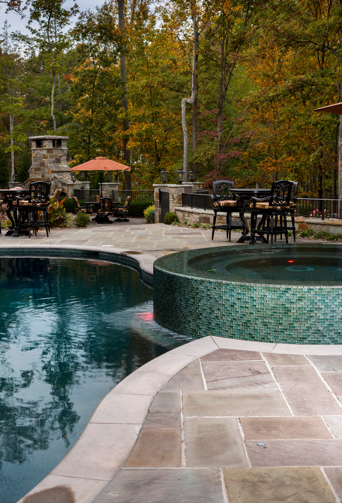 Expansive mediterranean back kidney-shaped natural hot tub in Charlotte with natural stone paving.
