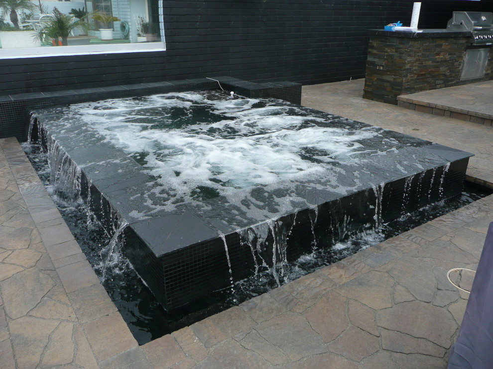 Immagine di una piccola piscina moderna rettangolare dietro casa con una vasca idromassaggio e cemento stampato