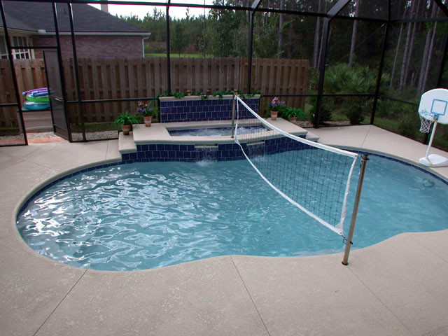 Immagine di una piscina monocorsia classica a "C" di medie dimensioni e dietro casa con una vasca idromassaggio e lastre di cemento