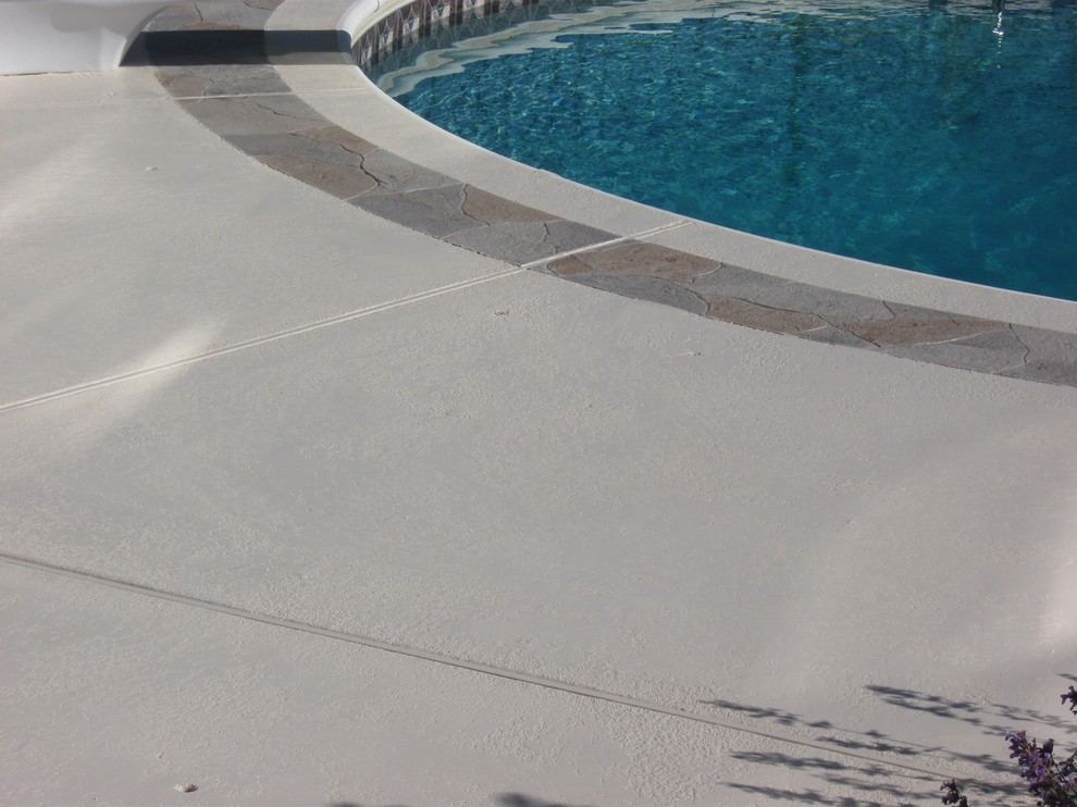 Imagen de piscina natural clásica de tamaño medio a medida en patio trasero con suelo de hormigón estampado