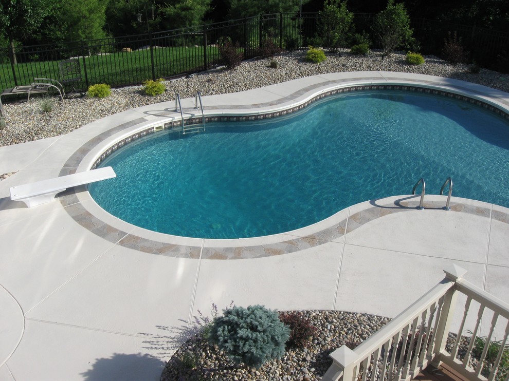 Ejemplo de piscina tradicional de tamaño medio a medida en patio trasero con suelo de hormigón estampado