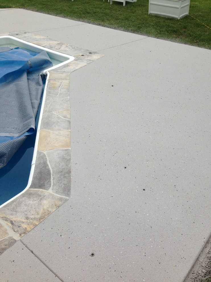 Foto de piscina alargada clásica rectangular en patio trasero con losas de hormigón