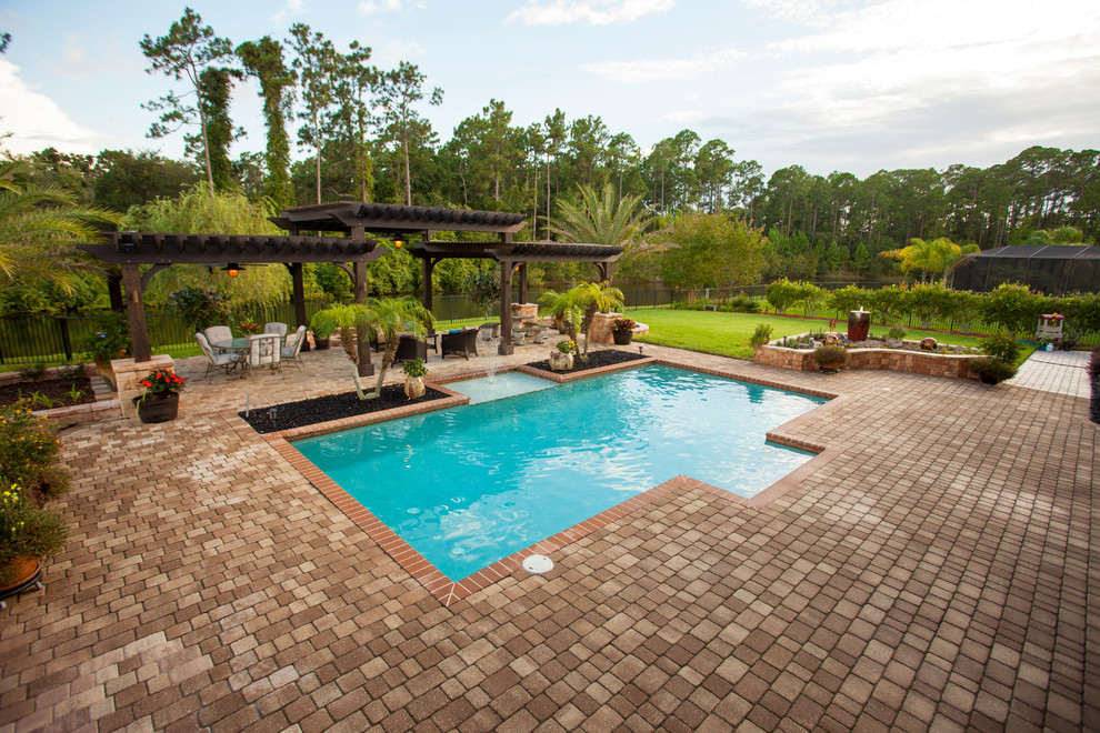 Cette photo montre une très grande piscine arrière et hors-sol chic rectangle avec des pavés en pierre naturelle et un point d'eau.