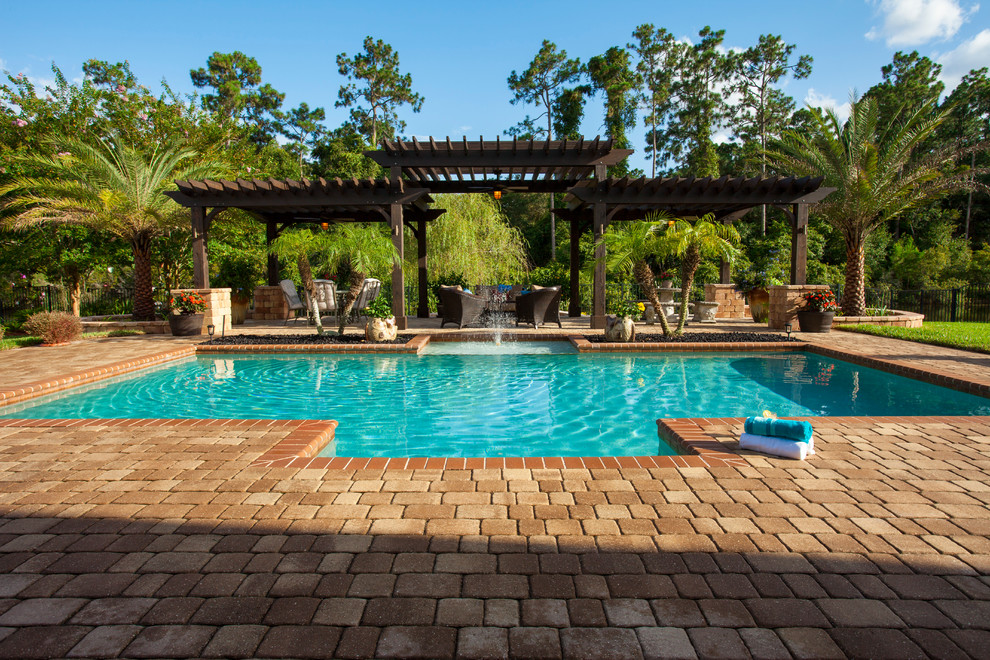 Imagen de casa de la piscina y piscina elevada clásica extra grande rectangular en patio trasero con adoquines de piedra natural