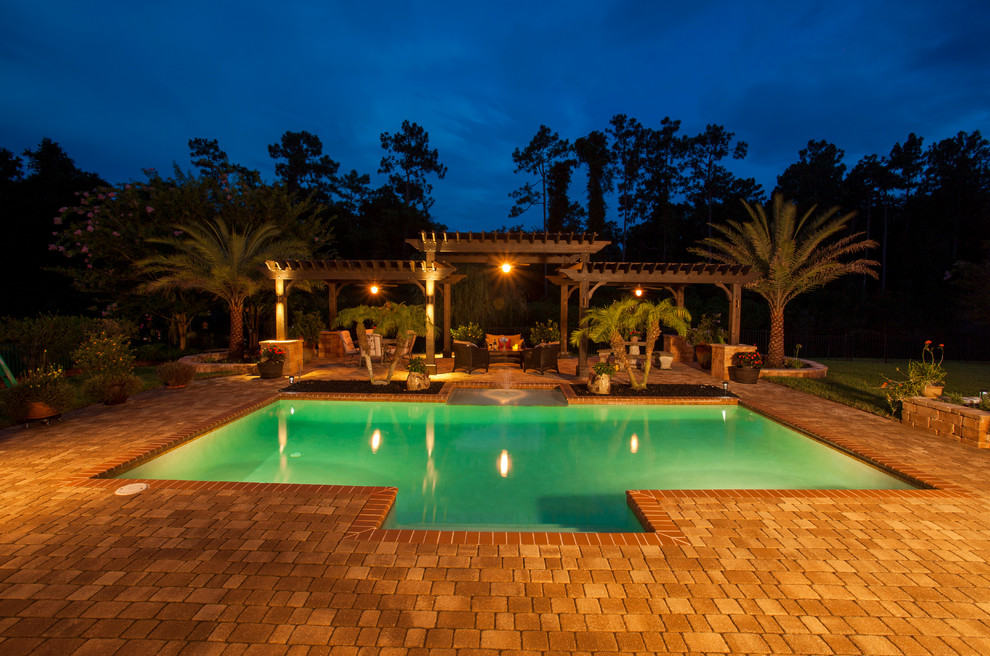Immagine di un'ampia piscina fuori terra tradizionale rettangolare dietro casa con pavimentazioni in pietra naturale e fontane
