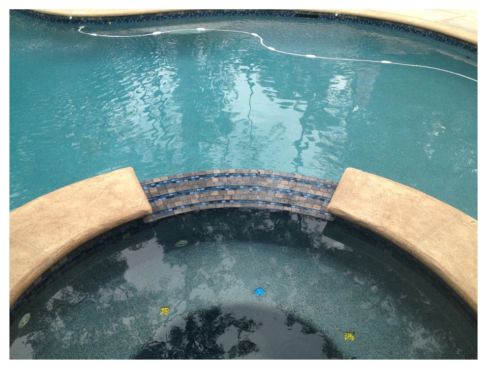 Example of a mid-sized classic backyard stone and custom-shaped hot tub design in Houston