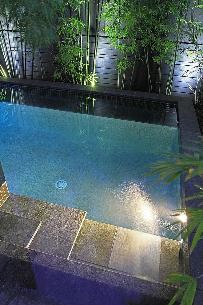 Ejemplo de piscina bohemia pequeña en forma de L en patio trasero con adoquines de piedra natural