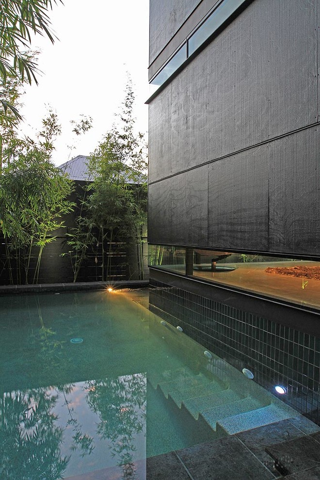 Imagen de piscina bohemia pequeña en forma de L en patio trasero con adoquines de piedra natural