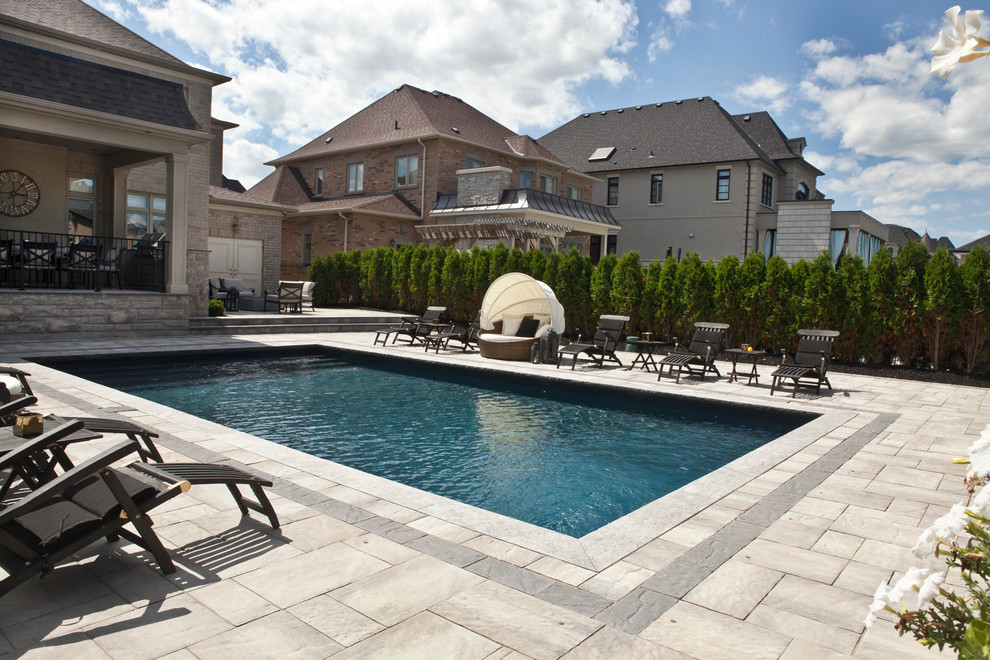Example of a large classic backyard stone and rectangular lap pool design in Toronto