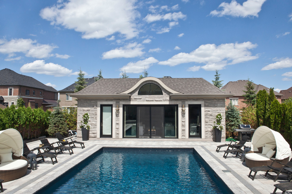 Пример оригинального дизайна: большой спортивный, прямоугольный бассейн на заднем дворе в классическом стиле с домиком у бассейна и покрытием из каменной брусчатки