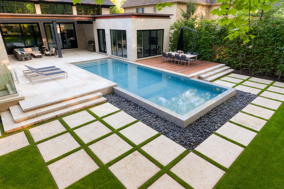 Photo of a large contemporary back rectangular infinity swimming pool in Other with a water feature and natural stone paving.