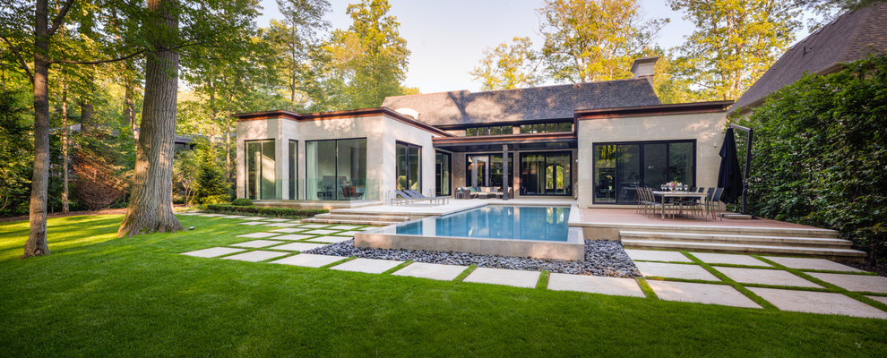 Diseño de piscina con fuente infinita contemporánea grande rectangular en patio trasero con adoquines de piedra natural