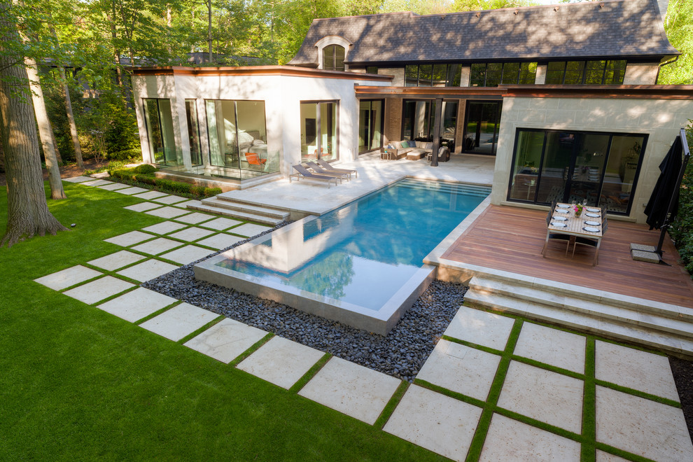Foto de piscina con fuente infinita contemporánea grande rectangular en patio trasero con adoquines de piedra natural