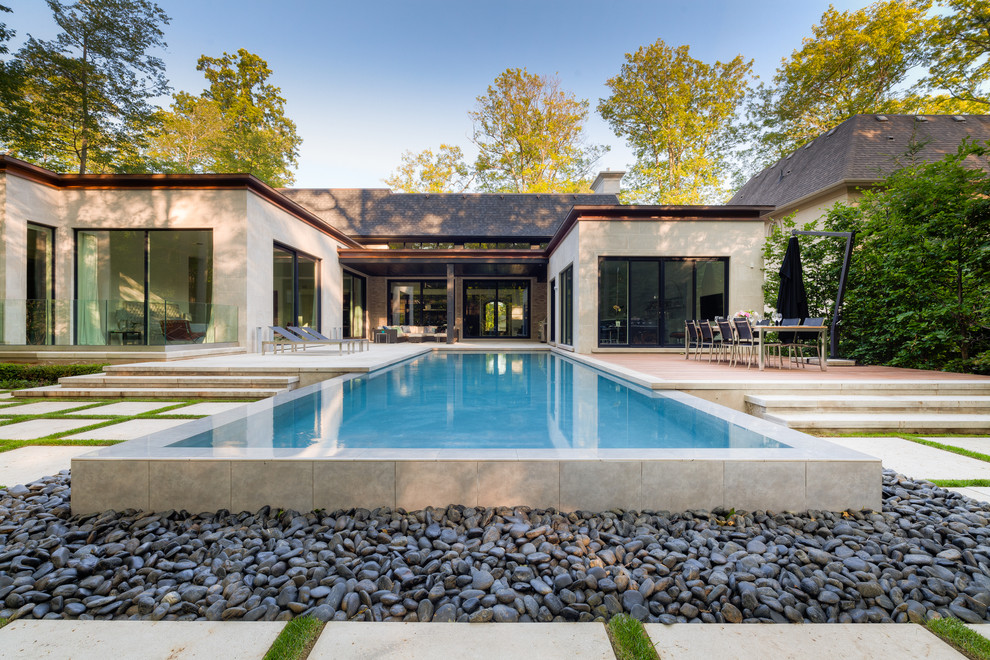 Imagen de piscina con fuente infinita contemporánea grande rectangular en patio trasero con adoquines de piedra natural