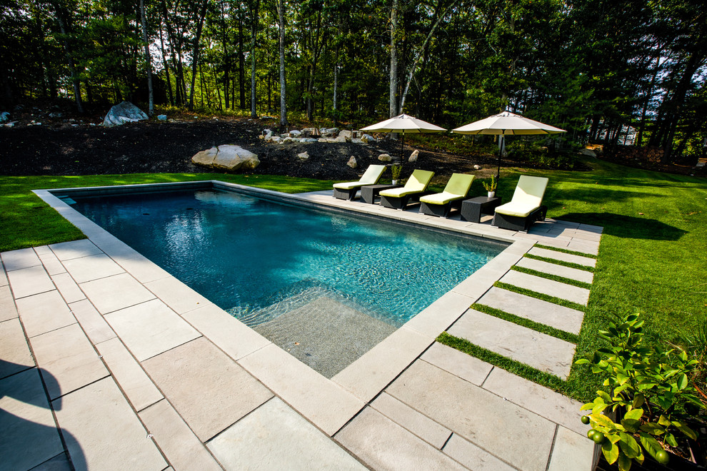 Réalisation d'une piscine design de taille moyenne et rectangle avec des pavés en pierre naturelle.