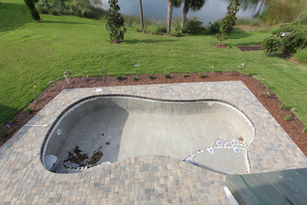 Пример оригинального дизайна: большой бассейн произвольной формы на заднем дворе в стиле неоклассика (современная классика) с мощением клинкерной брусчаткой