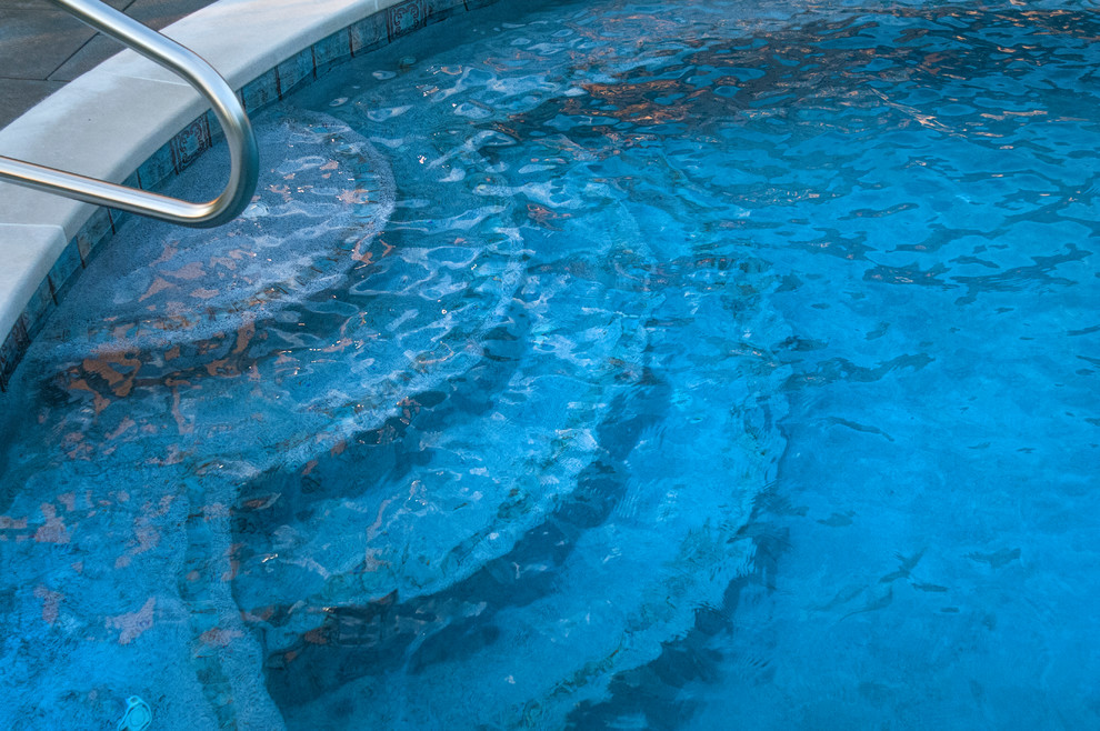 Réalisation d'une piscine naturelle et arrière tradition en forme de haricot de taille moyenne avec un bain bouillonnant et des pavés en pierre naturelle.
