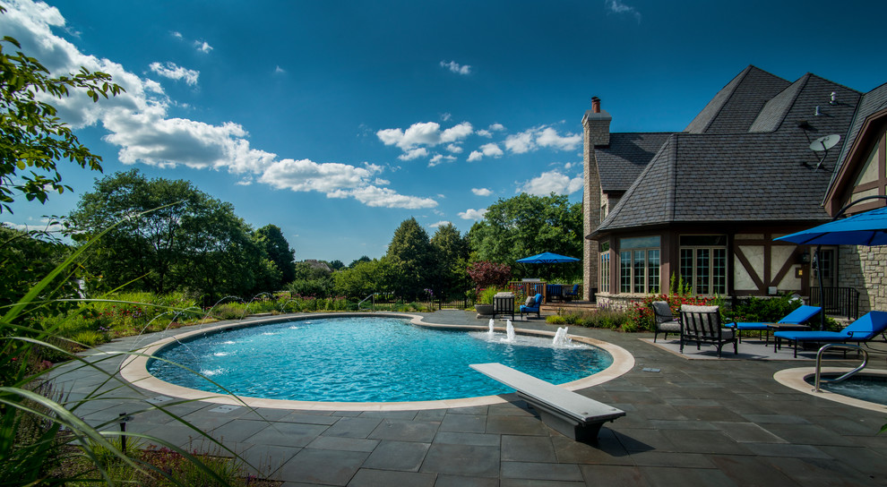Esempio di una piscina naturale chic a "C" di medie dimensioni e dietro casa con una vasca idromassaggio e pavimentazioni in pietra naturale