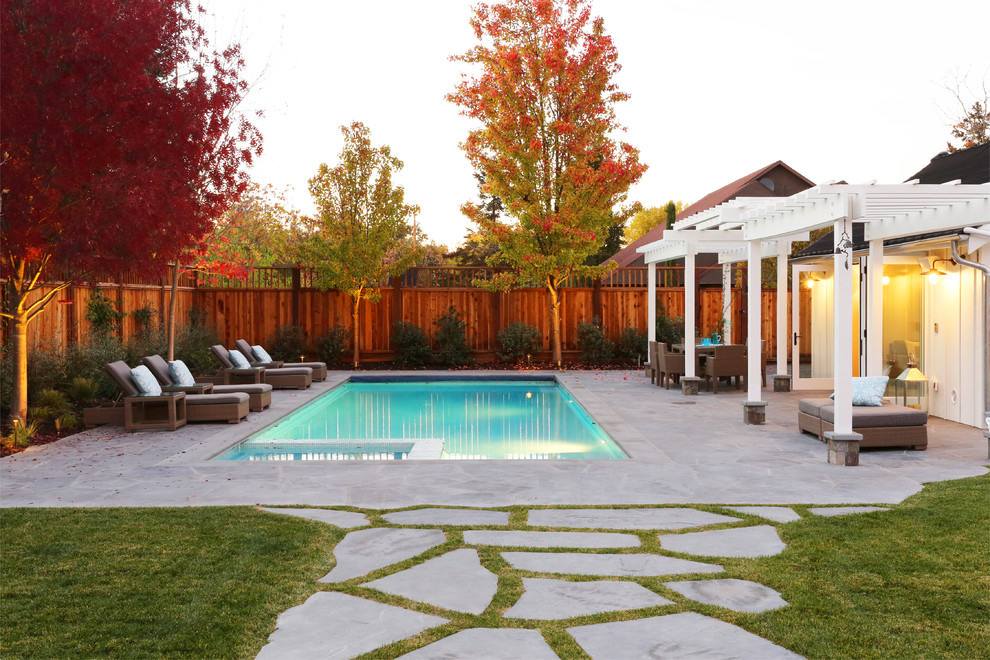 Immagine di una piscina classica rettangolare di medie dimensioni e dietro casa con pavimentazioni in pietra naturale e una vasca idromassaggio