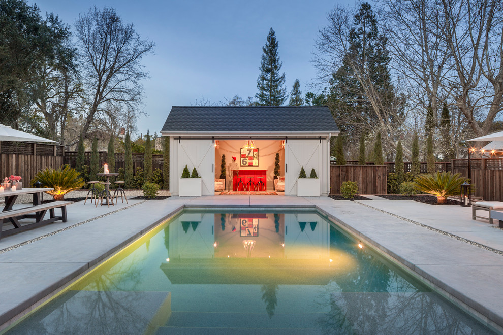 Modelo de casa de la piscina y piscina campestre de tamaño medio rectangular en patio trasero con adoquines de hormigón