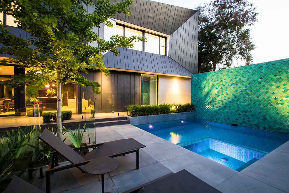 Esempio di una grande piscina minimal personalizzata con pavimentazioni in pietra naturale