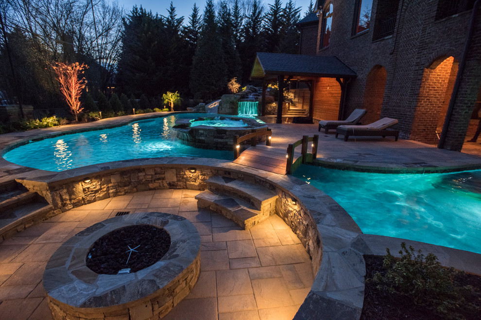 Стильный дизайн: огромный естественный бассейн произвольной формы на заднем дворе в морском стиле с водной горкой и покрытием из каменной брусчатки - последний тренд