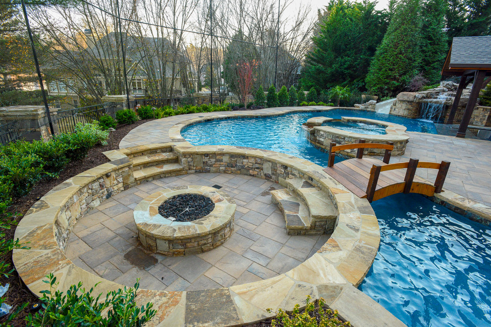 Пример оригинального дизайна: огромный естественный бассейн произвольной формы на заднем дворе в морском стиле с водной горкой и покрытием из каменной брусчатки
