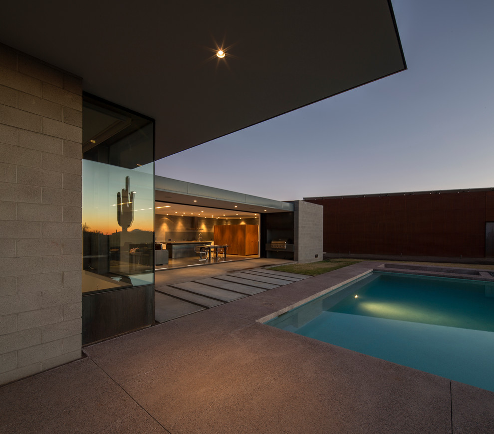 Foto di una piscina monocorsia minimalista rettangolare di medie dimensioni e dietro casa con una vasca idromassaggio e lastre di cemento