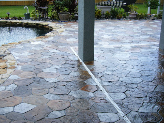 Ejemplo de piscina con fuente de tamaño medio redondeada en patio trasero con suelo de hormigón estampado