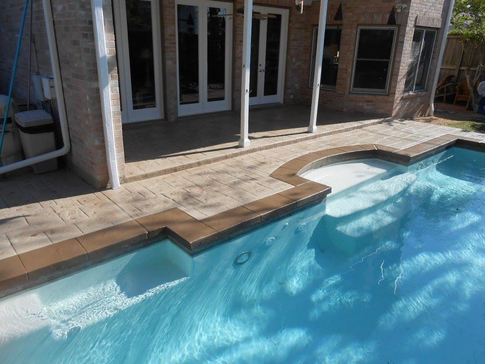 Foto de piscina actual de tamaño medio a medida en patio trasero con adoquines de hormigón