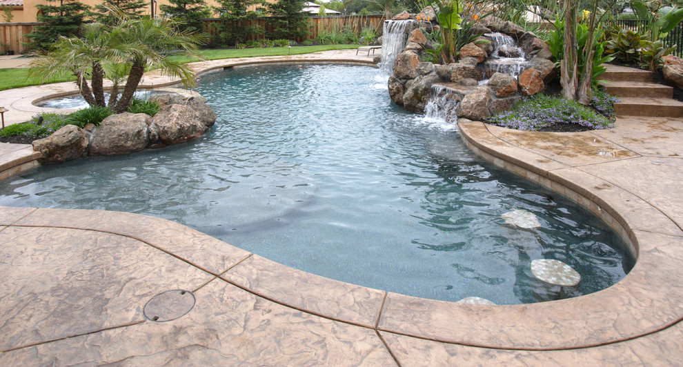 Design ideas for a large traditional back kidney-shaped natural swimming pool in Toronto with a water feature and stamped concrete.