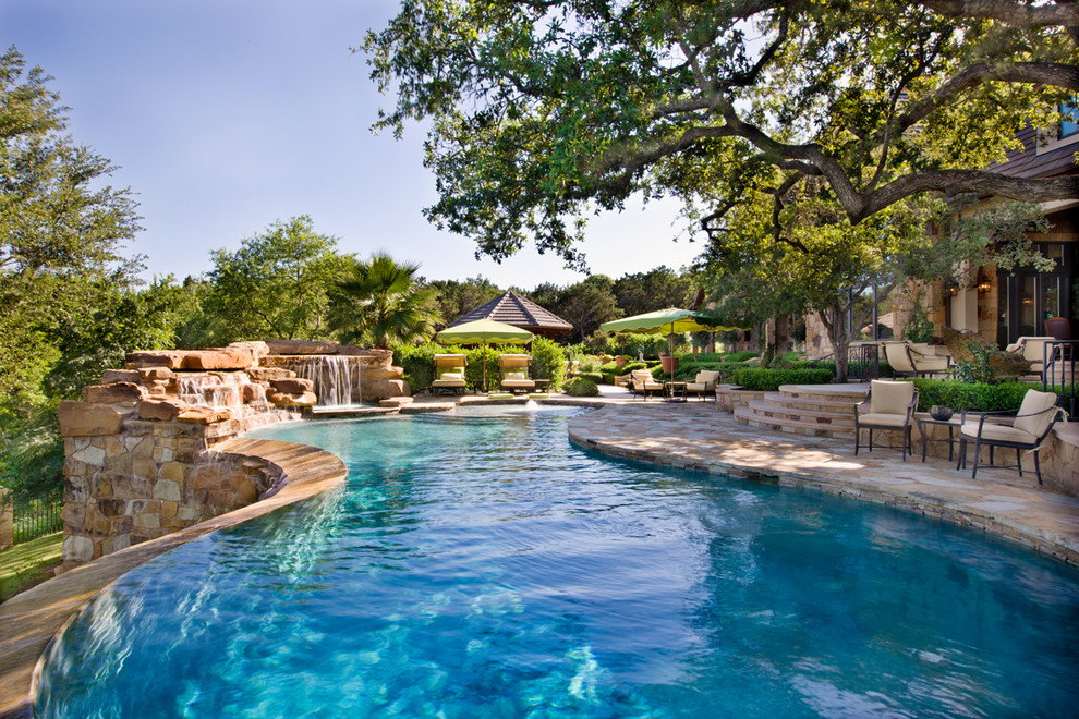 Photo of a traditional custom shaped natural swimming pool in Austin with natural stone paving.