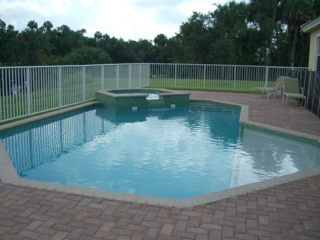 Foto de piscina con fuente alargada tradicional de tamaño medio a medida en patio trasero con adoquines de ladrillo