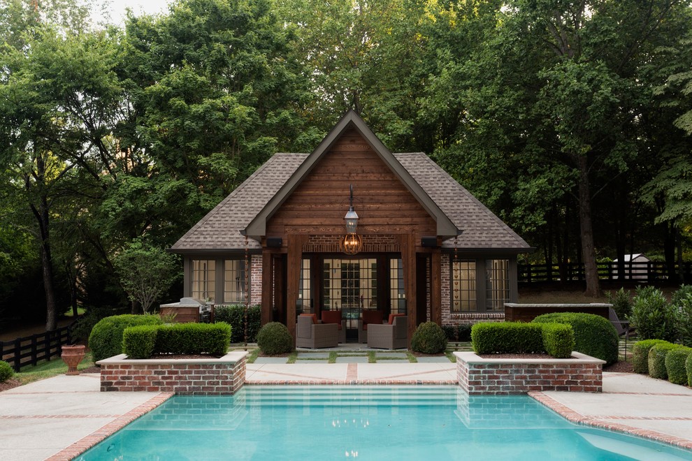 This is an example of a large classic back custom shaped swimming pool in Nashville with a pool house and concrete paving.