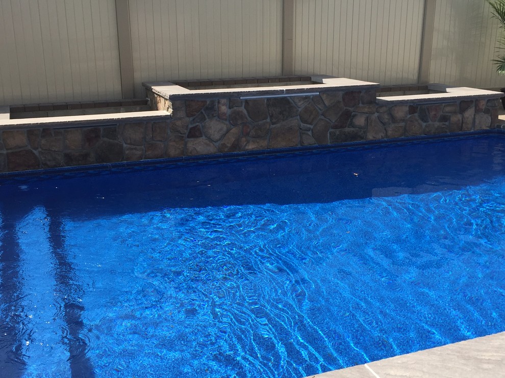 Ejemplo de piscina con fuente clásica en patio trasero
