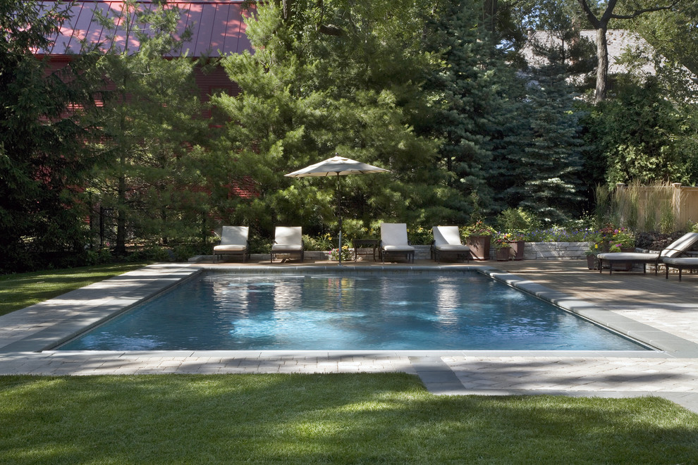 This is an example of a modern back rectangular swimming pool in Chicago with natural stone paving.