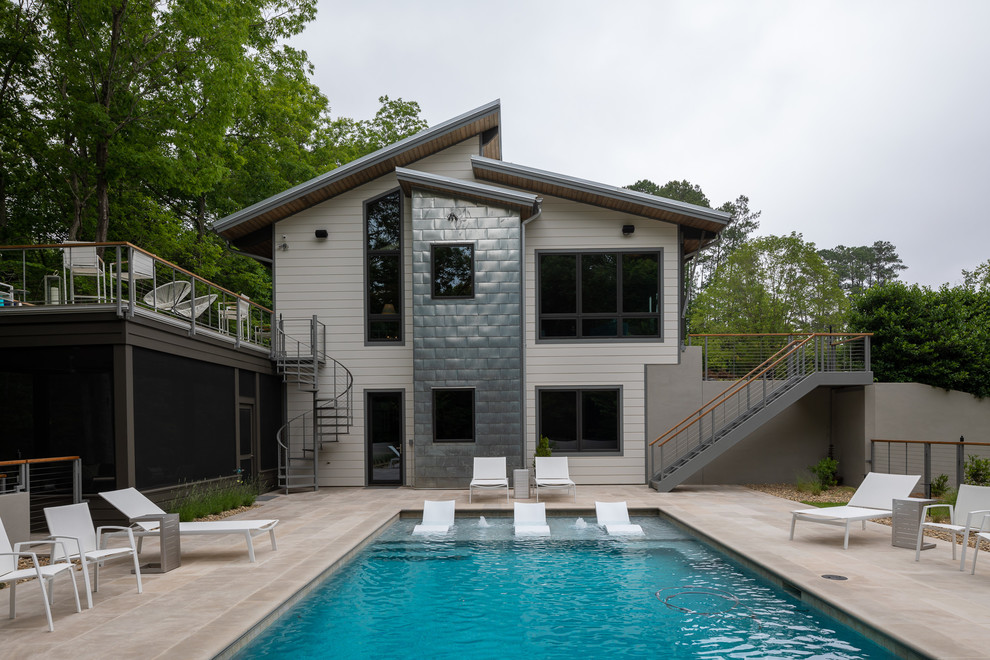 Immagine di una piscina a sfioro infinito stile marino rettangolare di medie dimensioni e dietro casa con fontane e lastre di cemento
