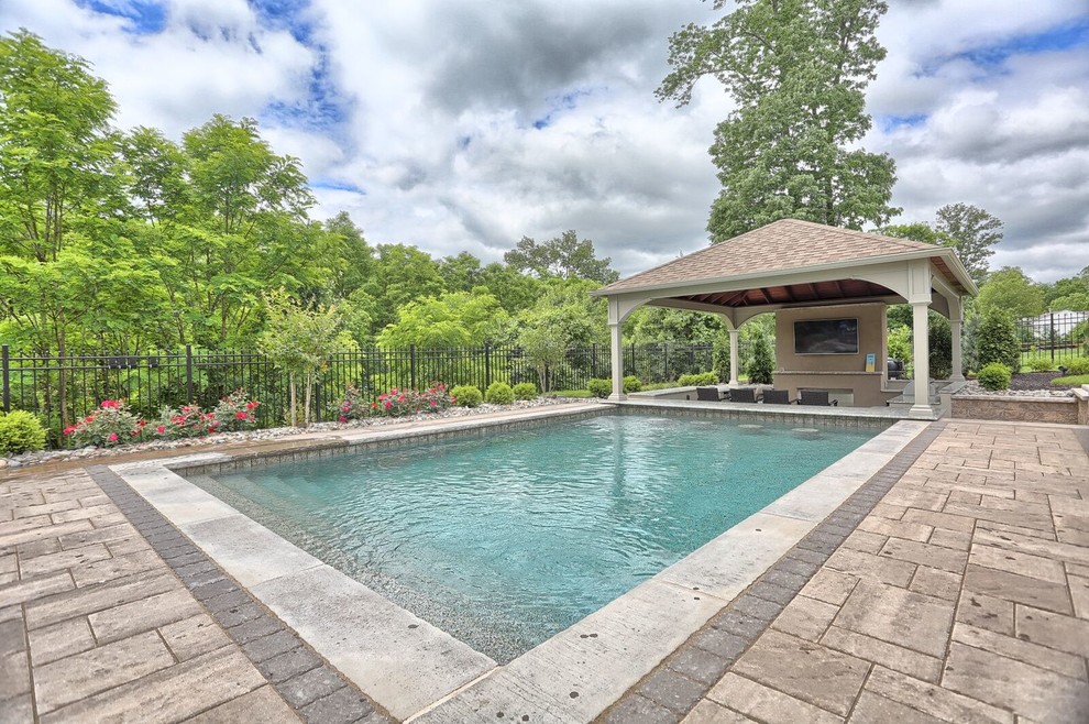 Ispirazione per una grande piscina monocorsia tradizionale rettangolare dietro casa con una dépendance a bordo piscina e pavimentazioni in cemento